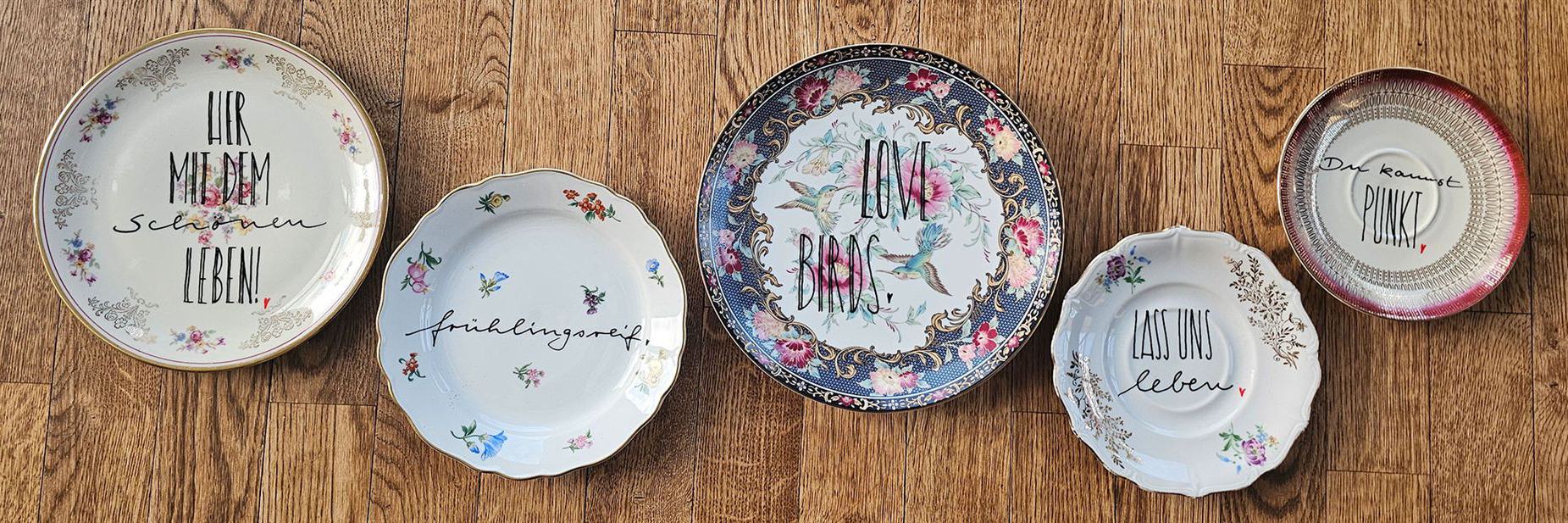 Elegante Vintage-Teller mit kreativen Sprüchen und floralen Designs.