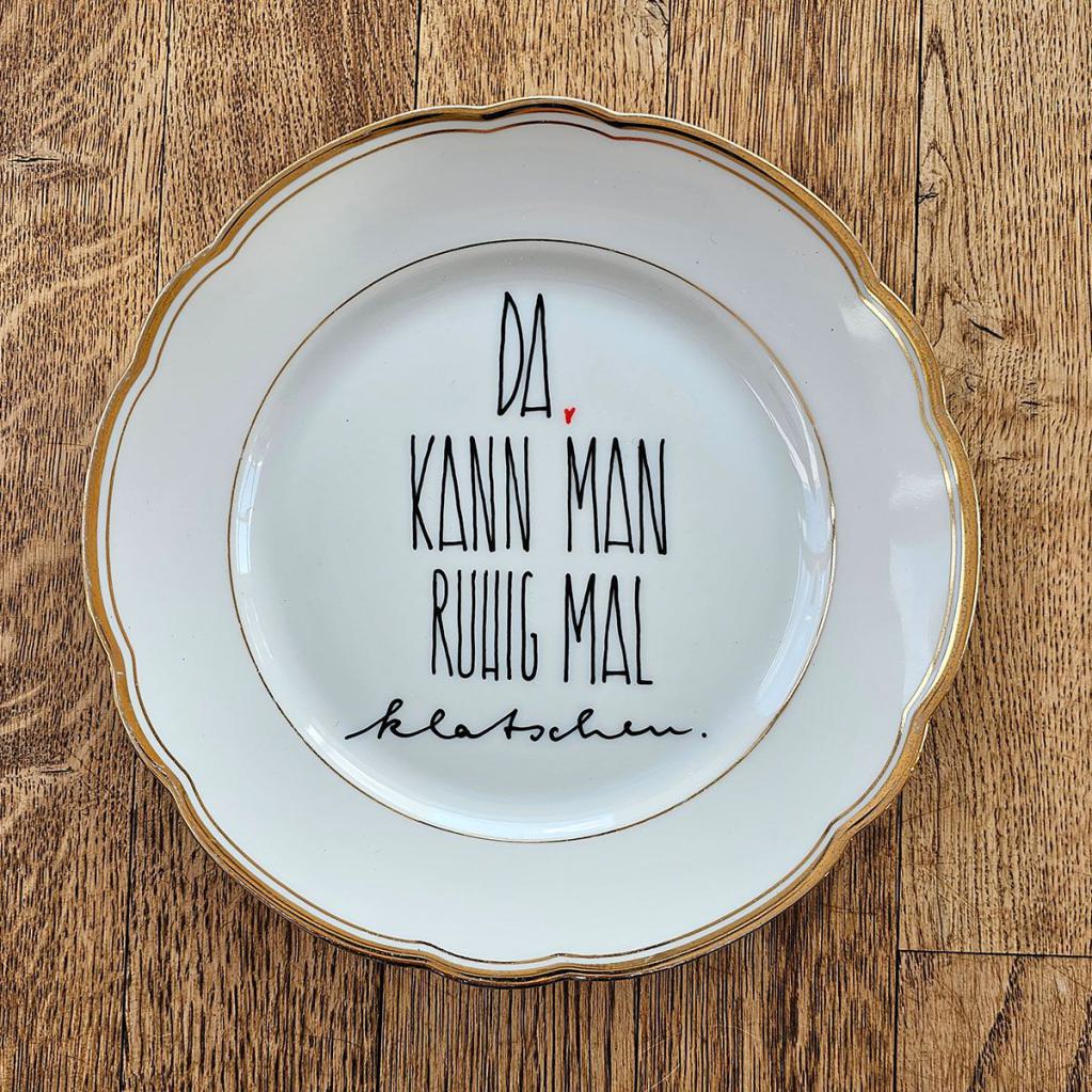  Künstlerischer Vintage-Teller mit Goldrand und inspirierendem Spruch 'Da kann man ruhig mal klatschen'.